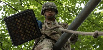 A Cadet lowers a milk crate filled with pieces of wood on and FLRC obstacle.