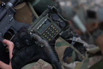A Cadet fiddles with a radio during FTX.