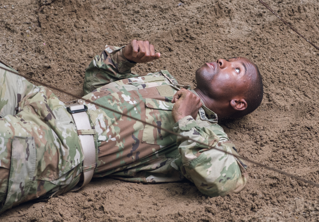 A Cadet scoots on his back through the low wire.