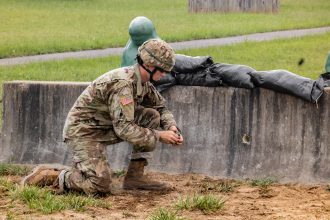 A Cadet prepares to throw a dummy grenade in kneeling position